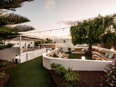 Moderner Außenbereich eines Hotels mit Sitzgelegenheiten und Beleuchtung bei Sonnenuntergang.