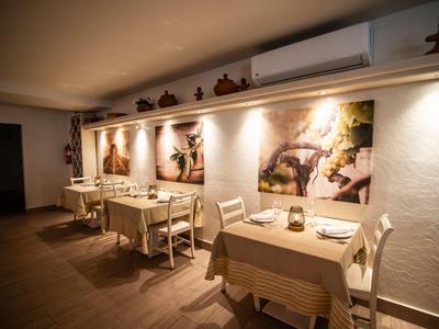 Gemütlicher Gastraum mit Holztischen, Stühlen, warmem Licht und dekorativen Wandfiguren.