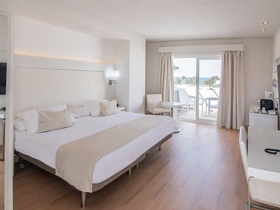 Helles, modernes Schlafzimmer mit großem Bett, Holzfußboden und Terrasse mit Blick ins Freie.