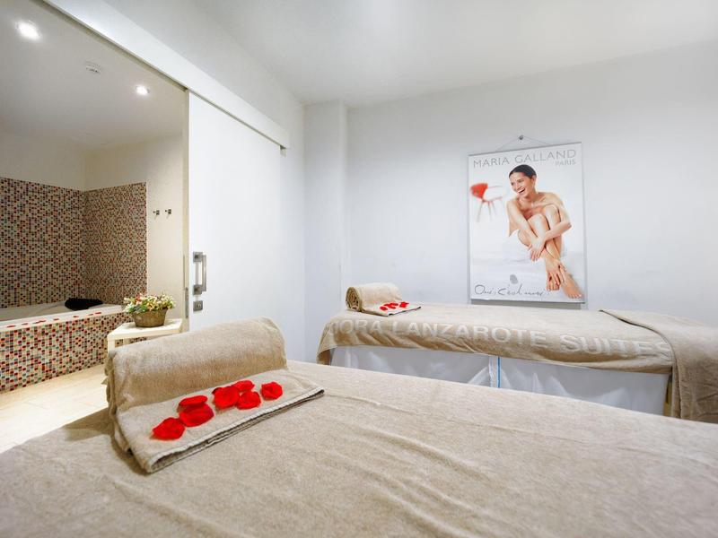 Heller Wellnessraum mit Massagebetten und Blick in einen Bereich mit Whirlpool.