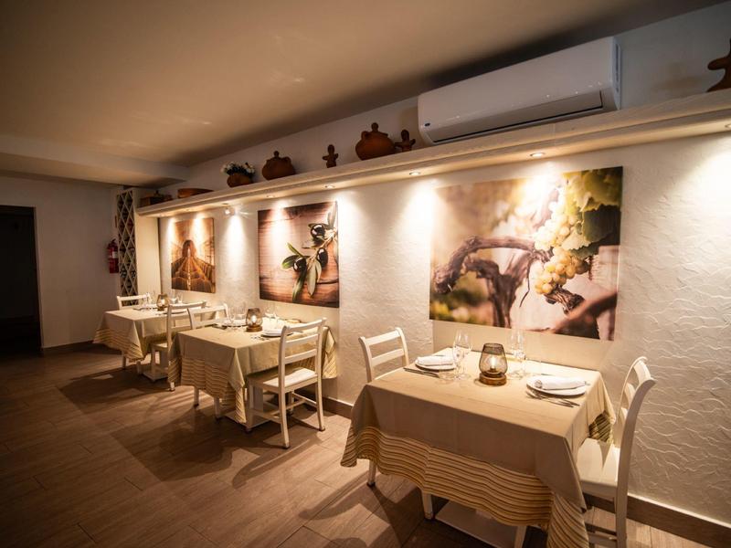 Gemütlicher Gastraum mit Holztischen, Stühlen, warmem Licht und dekorativen Wandfiguren.