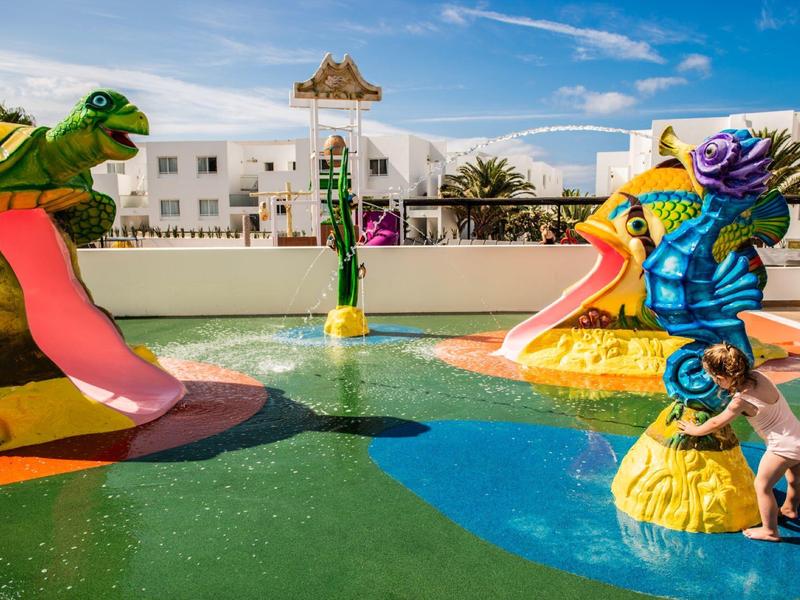 Bunter Kinderspielplatz mit Wasserrutschen in tierischen Formen und Wasserbecken im Freien.