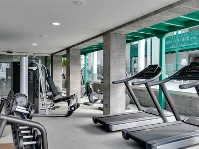 Modernes Fitnessstudio mit Laufbändern, Kraftgeräten und großem Fenster für Tageslicht.