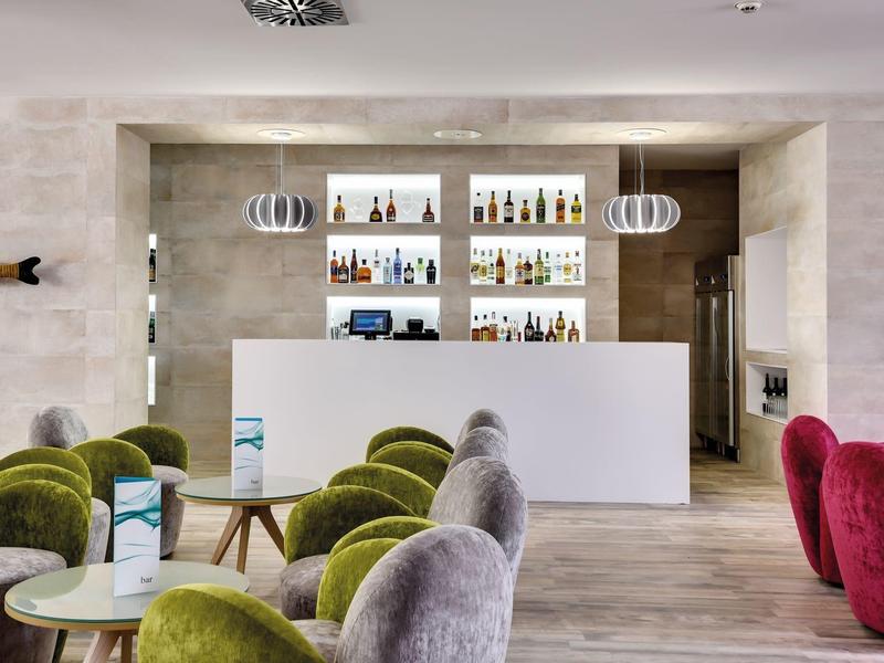 Hall d'hotel moderno con poltrone colorate e banco bianco elegante.