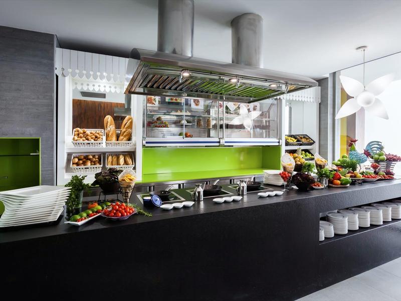 Cucina moderna con bancone nero, scaffali di pane e decorazioni verdi.