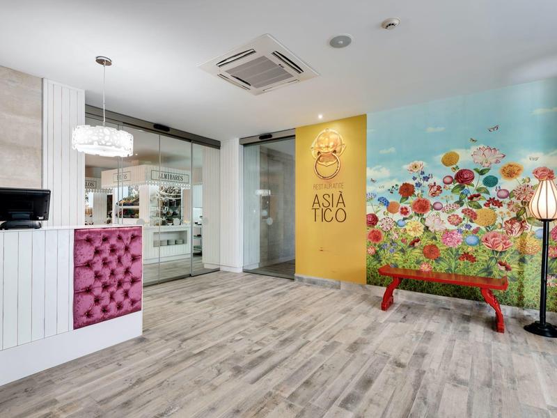 Reception moderna con banco bianco, parete colorata e panca rossa in un elegante hotel.