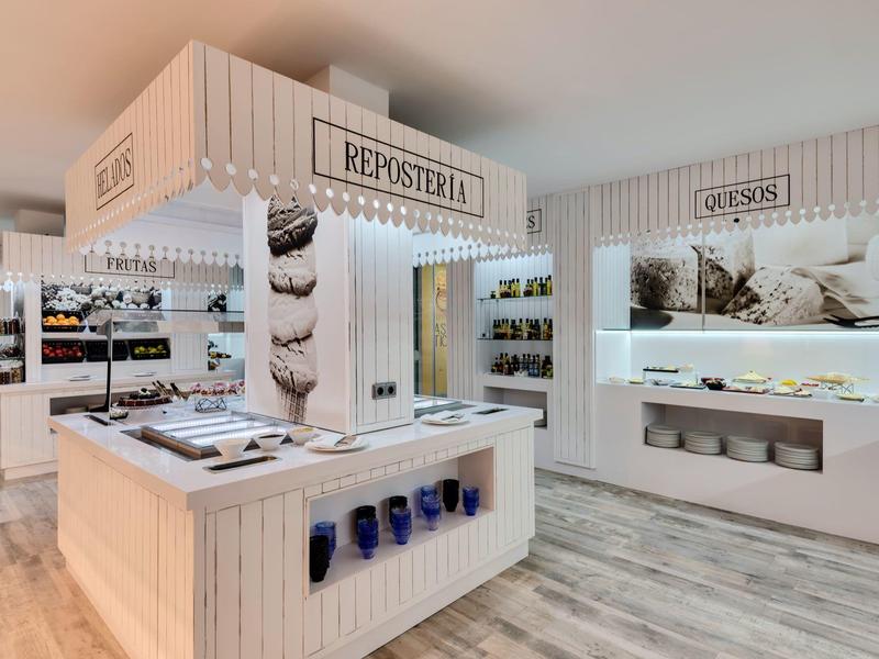 Interno moderno di un negozio di souvenir con espositori bianchi e illuminazione morbida.