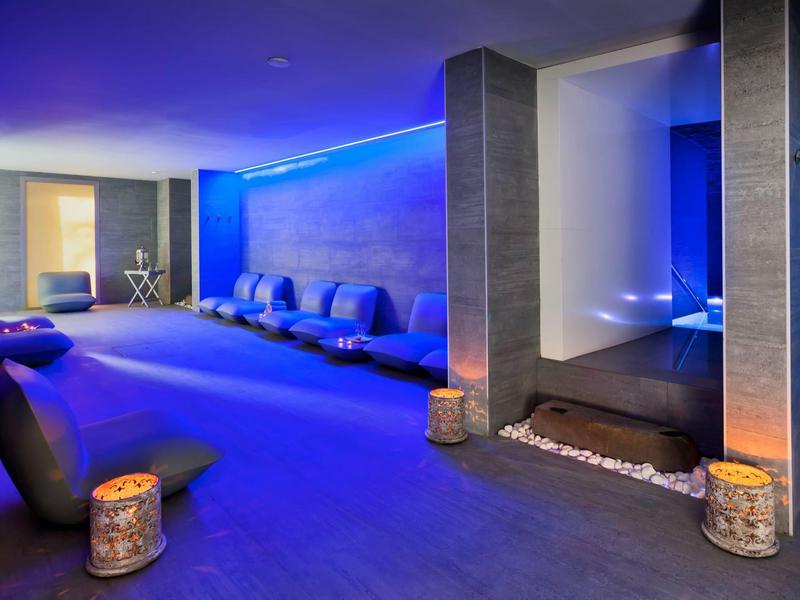 Salotto spa moderno con illuminazione blu e comode sedute per il relax.