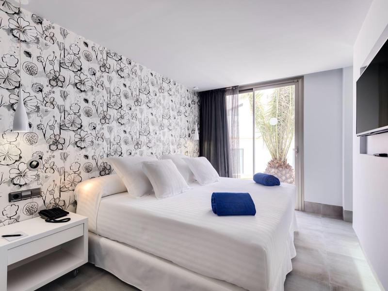 Camera d'hotel moderna con due letti, decorazione monocromatica e balcone luminoso.