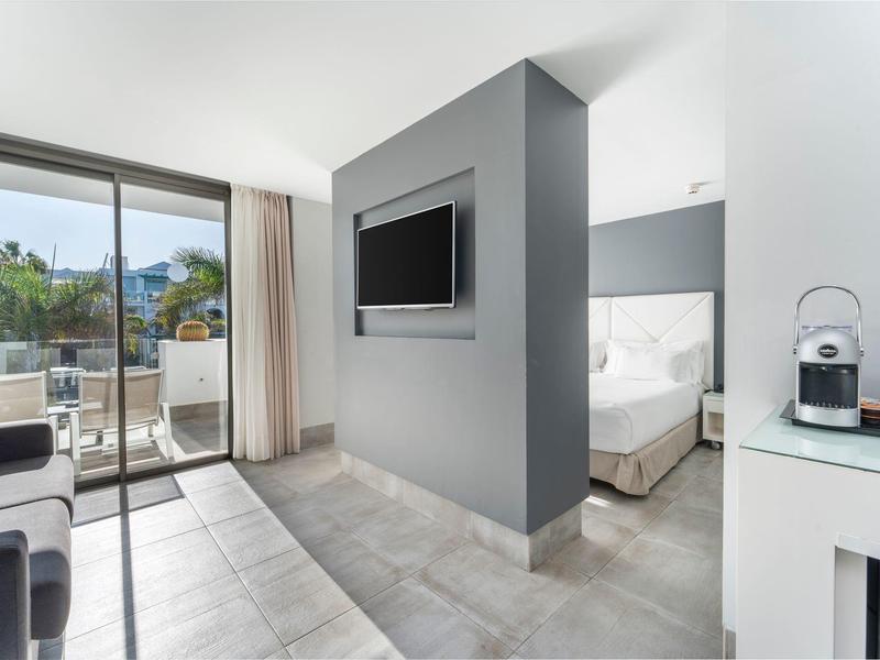 Camera d'hotel moderna con terrazza, TV a parete e macchina per caffè.