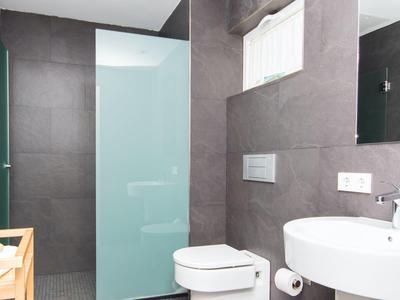 Modern bathroom with gray tiles, white fixtures, and a wooden crate.