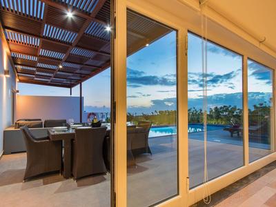 Modern outdoor seating area with furniture and pool view at sunset.