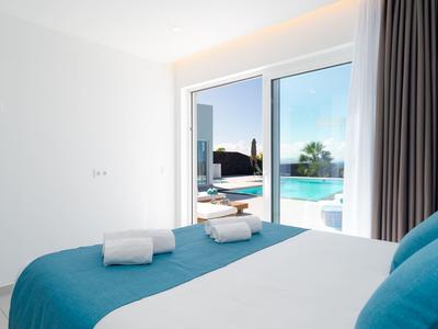 Modern bedroom with blue bed and direct access to the pool area through large glass sliding doors.