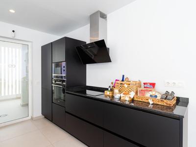 Moderne schwarze Küchenzeile mit eingebauten Geräten und Frühstückskorb auf der Arbeitsplatte