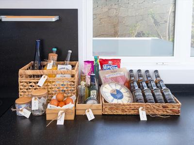 Various breakfast items like jam, honey, and biscuits in baskets on a kitchen counter.