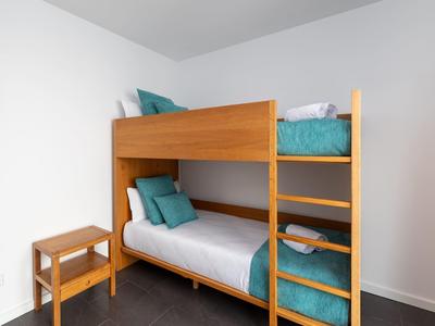 Small room with wooden bunk bed and turquoise pillows and blankets.
