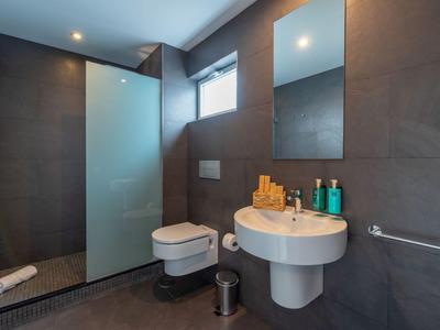 Modernes Badezimmer mit Dusche, Wandtoilette, Waschbecken und dunklen Fliesen.