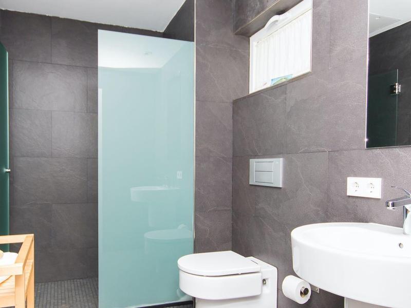 Modern bathroom with gray tiles, white fixtures, and a wooden crate.