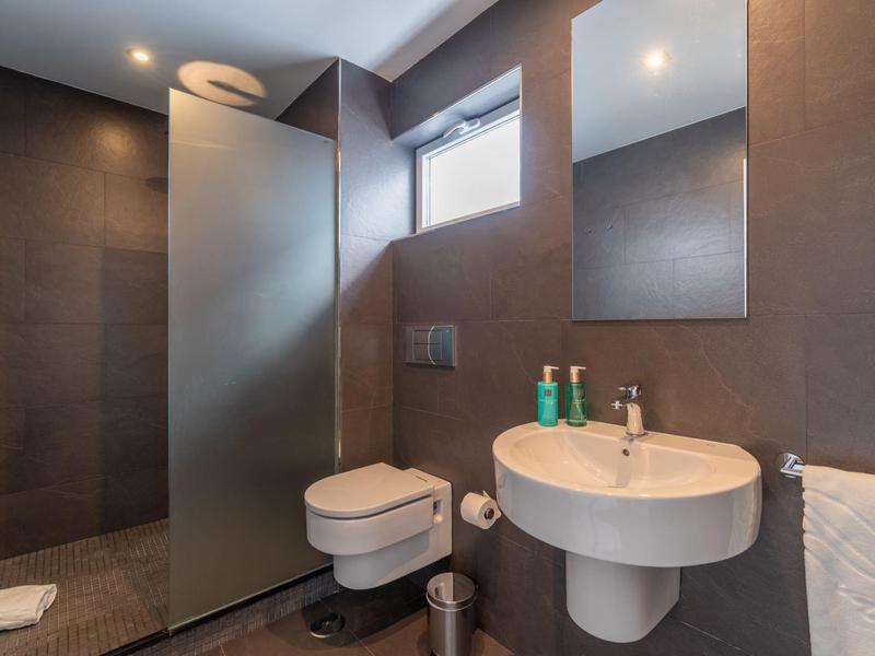 Modern bathroom with round sink, wall-mounted toilet, and walk-in shower with glass partition