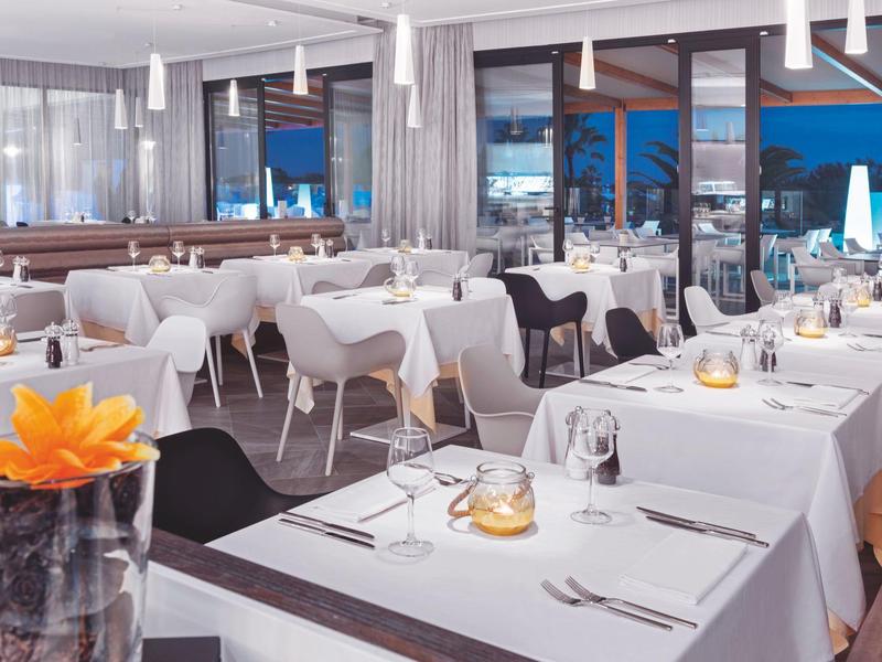 Restaurante elegante con mesas vestidas de blanco y gran ventana con vista nocturna