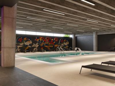 Modern indoor pool area with ceiling lights and loungers in a hotel