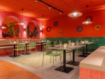 Modernes, farbenfrohes Restaurant mit grünen Stühlen und roten Wänden für entspannte Mahlzeiten.