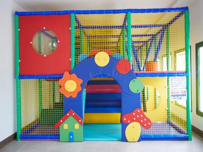 Buntes Indoor-Klettergerüst mit Netz, Tunnel und verschiedenen Formen in einem Raum.