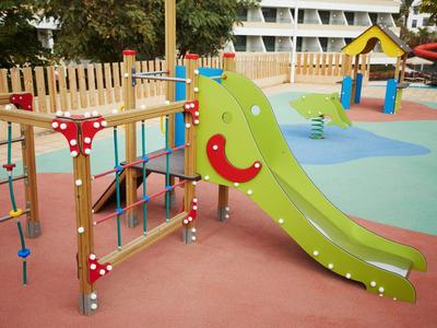 Bunter Spielplatz mit grünem Rutsche, Klettergerüst und bunter Gummimattefläche.