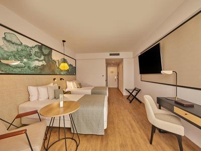 Modernes Hotelzimmer mit zwei Betten, Holzfußboden, Wandbild und Schreibtisch mit Stuhl.