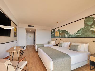 Modernes Hotelzimmer mit großem Bett, Holzboden, hellem Interieur und Kunst an der Wand.