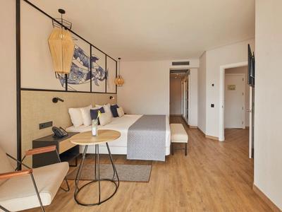 Modern eingerichtetes Hotelzimmer mit Doppelbett, Holzboden, runden Tischen und Wandbildern.