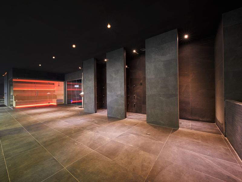 Moderner, dunkler Raum mit großem Fenster und rot beleuchtetem Bereich im Hintergrund.