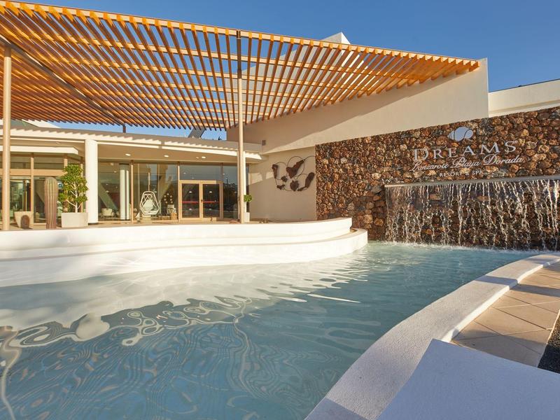 Moderner Außenbereich mit Pool, Wasserfall und Holzpergola bei sonnigem Wetter.