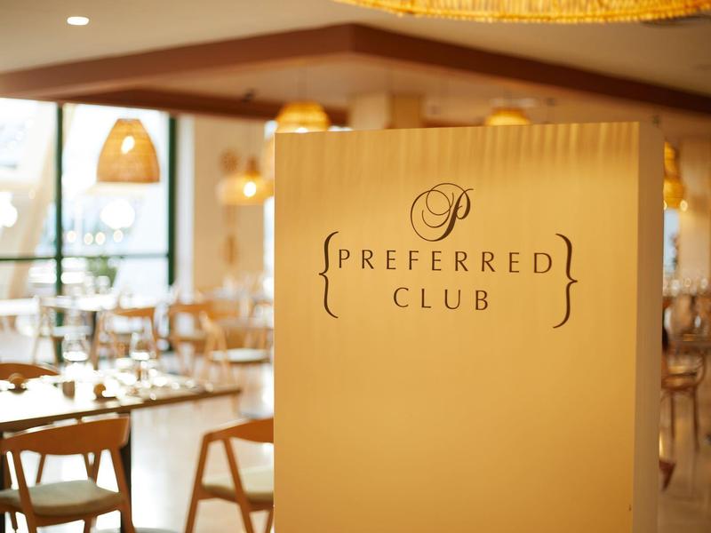 Eleganter Innenraum eines Restaurants mit weiß-gelben Wänden und einem Schild ?Preferred Club?.