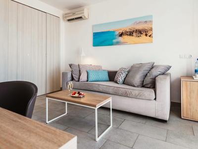 Modern eingerichtetes Wohnzimmer mit grauem Sofa, Holztisch und Strandbild an der Wand.
