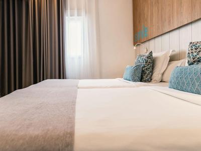 Helles Hotelzimmer mit großem Bett, Holzakzenten und dekorativen Kissen.