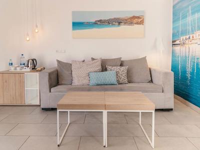 Helles Wohnzimmer mit grauem Sofa, Holztisch und maritimer Wanddekoration in einem Hotel.