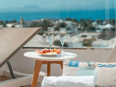 Zwei Sessel mit einem Tisch, auf dem Snacks und zwei gefüllte Champagnergläser stehen, mit Meerblick.