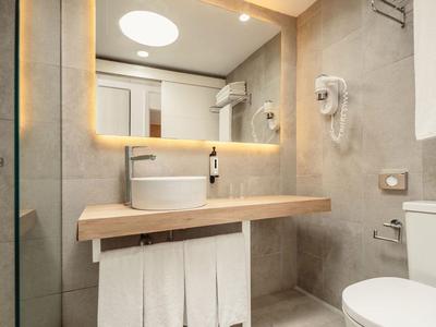 Modernes Badezimmer mit Waschbecken, Spiegel, Toilette und Duschecke in warmen Farbtönen.