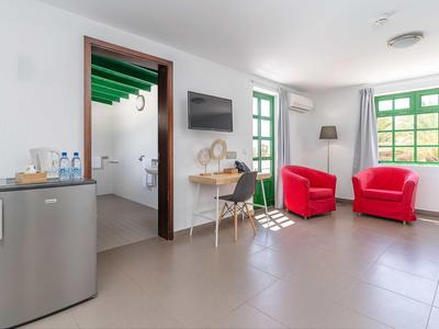 Helle, moderne Wohnküche mit roten Sesseln, großem Fenster, Schreibtisch und Mini-Kühlschrank.