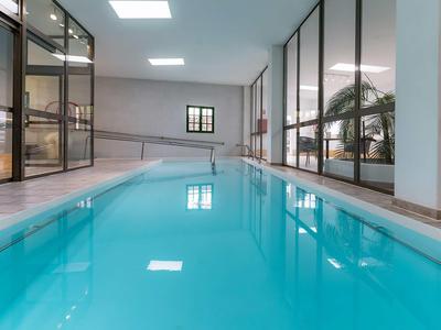 Innenpool mit klarem Wasser und Glaswänden in einem modernen Hotelbereich.