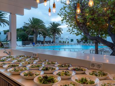 Buffet mit Salaten an einem Poolbereich in einem Hotel mit Palmen