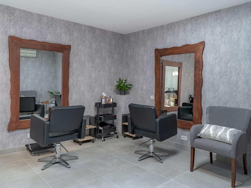 Moderner Friseursalon mit grauen Stühlen, großen Spiegeln und grauer Wand- und Bodenfarbe.
