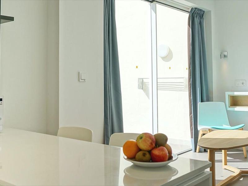 Modern living area with dining table, microwave, and daybed by floor-to-ceiling window.