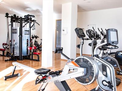 Salle de sport moderne avec divers appareils d'exercice et sol en bois clair.