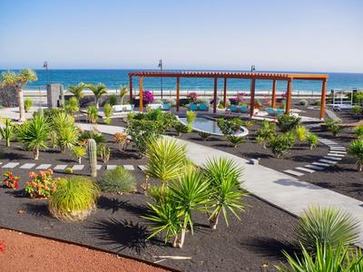 Moderner Hotelgarten mit gepflegtem Weg, Pflanzen und Blick aufs Meer im Hintergrund
