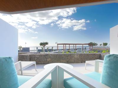 Sitzbereich mit Blick aufs Meer, zwei Stühle und Tisch auf Terrasse unter blauem Himmel