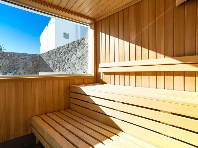 Helle Sauna mit Holzverkleidung und großer Fensteröffnung, durch die Tageslicht strömt.