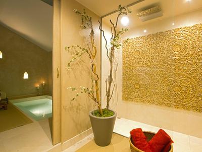Moderne Hotellobby mit Pflanzen, dekorativer Wand und Blick auf einen beleuchteten Pool.