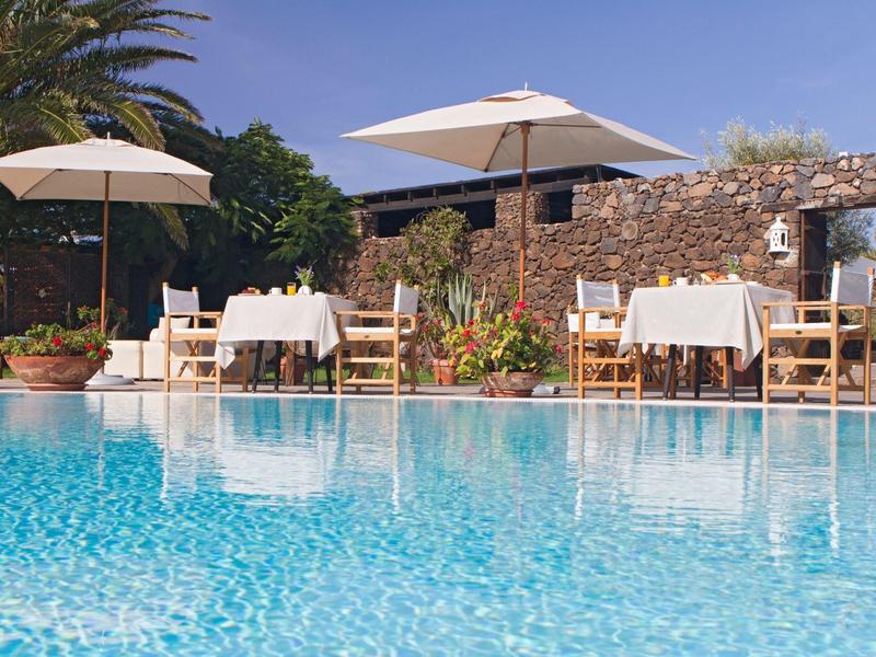 Einladender Pool mit klarem blauem Wasser, weißen Sonnenschirmen und gedeckten Tischen im Freien.